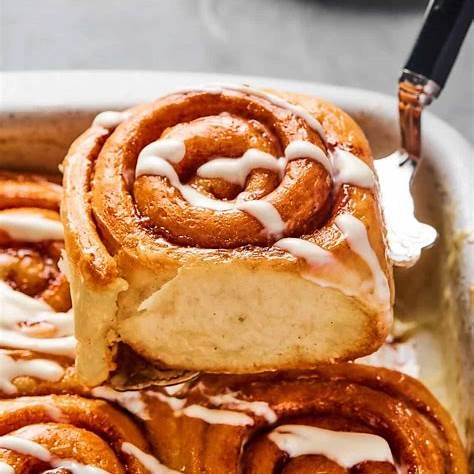 Freshly baked cinnamon roll with icing on a spatula