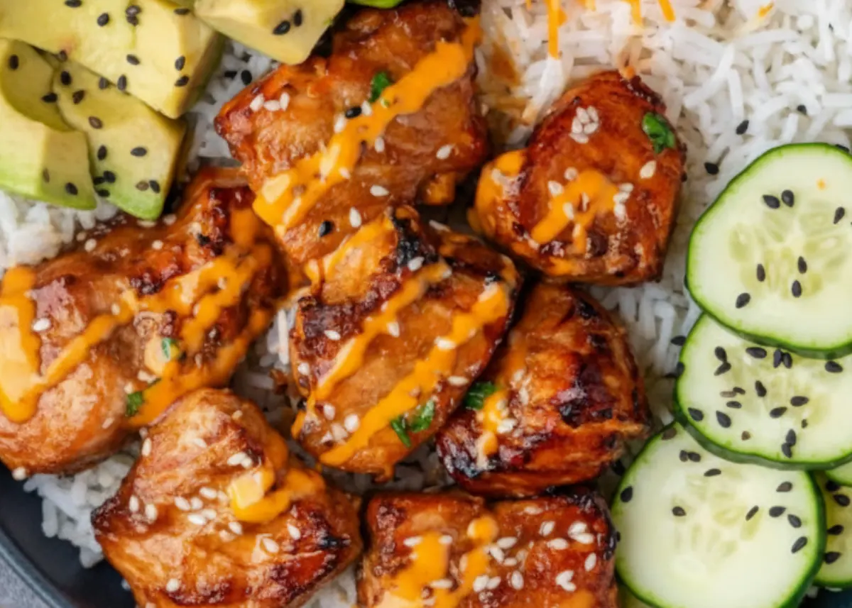 Close-up of caramelized salmon bites drizzled with spicy aioli