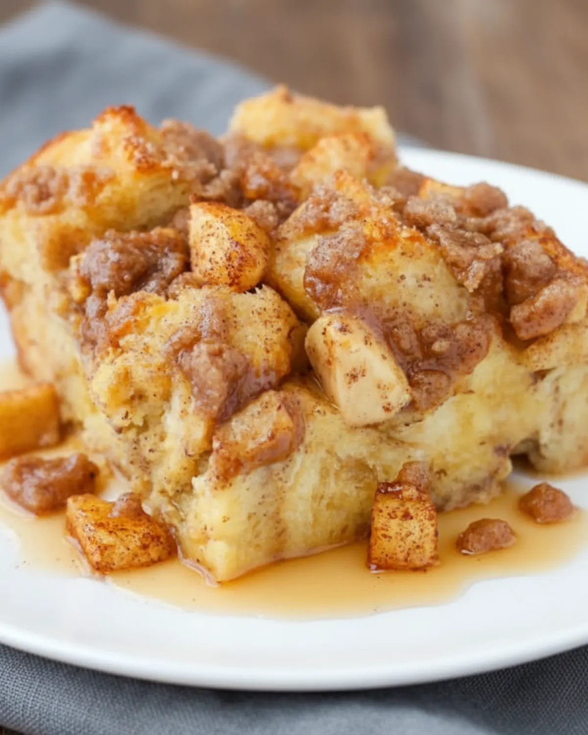 Slice of Overnight Apple Crisp Casserole on a white plate with cinnamon apples