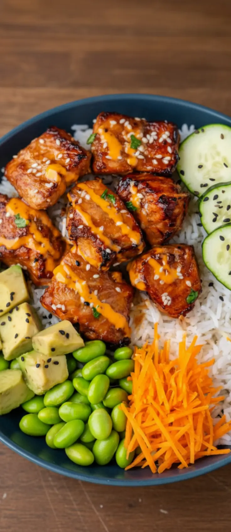 Salmon bowl with caramelized salmon bites, rice, cucumbers, avocado, edamame, and shredded carrots