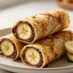 Banana chocolate roll-ups stacked on plate