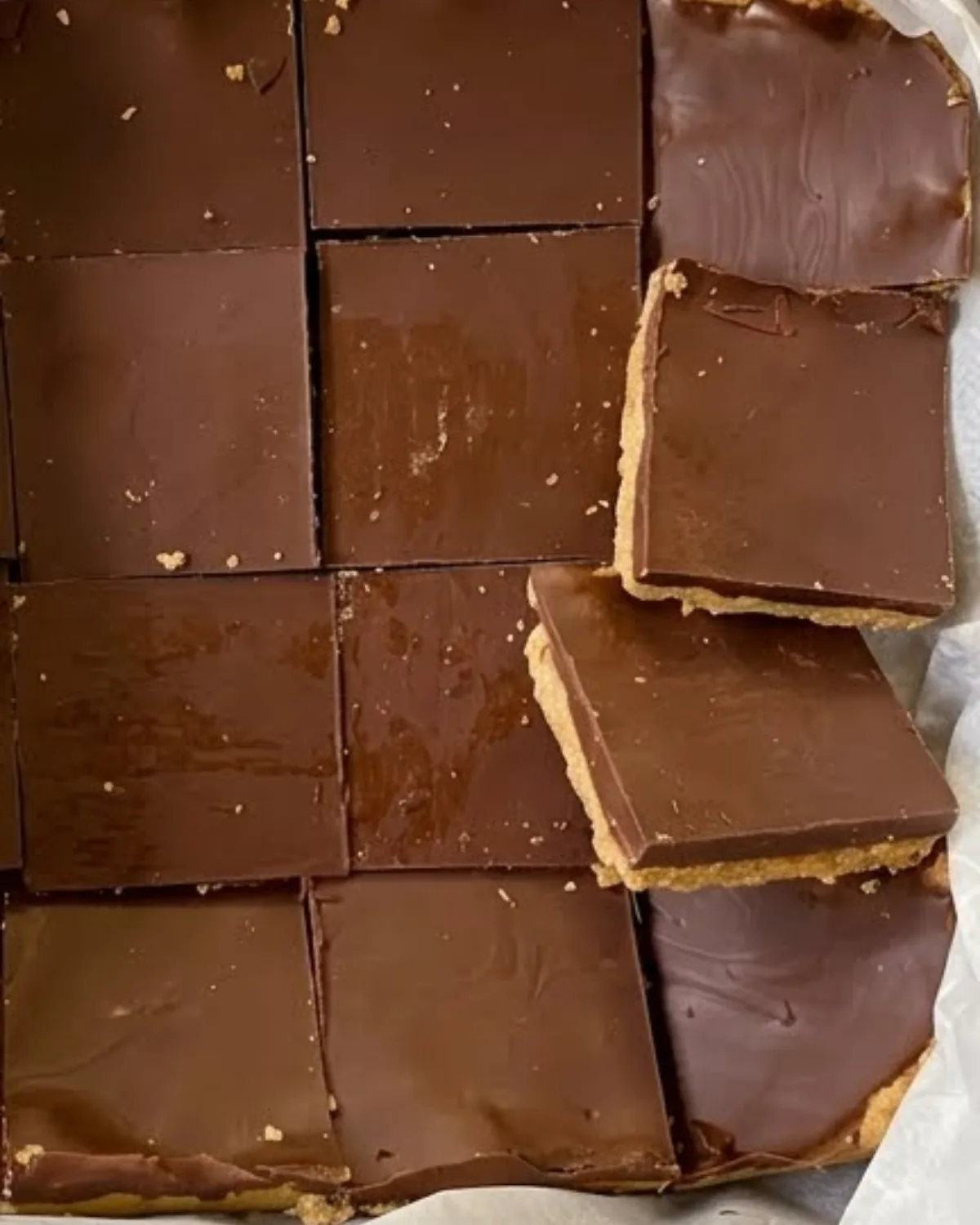 square chocolate peanut butter bars on parchment paper